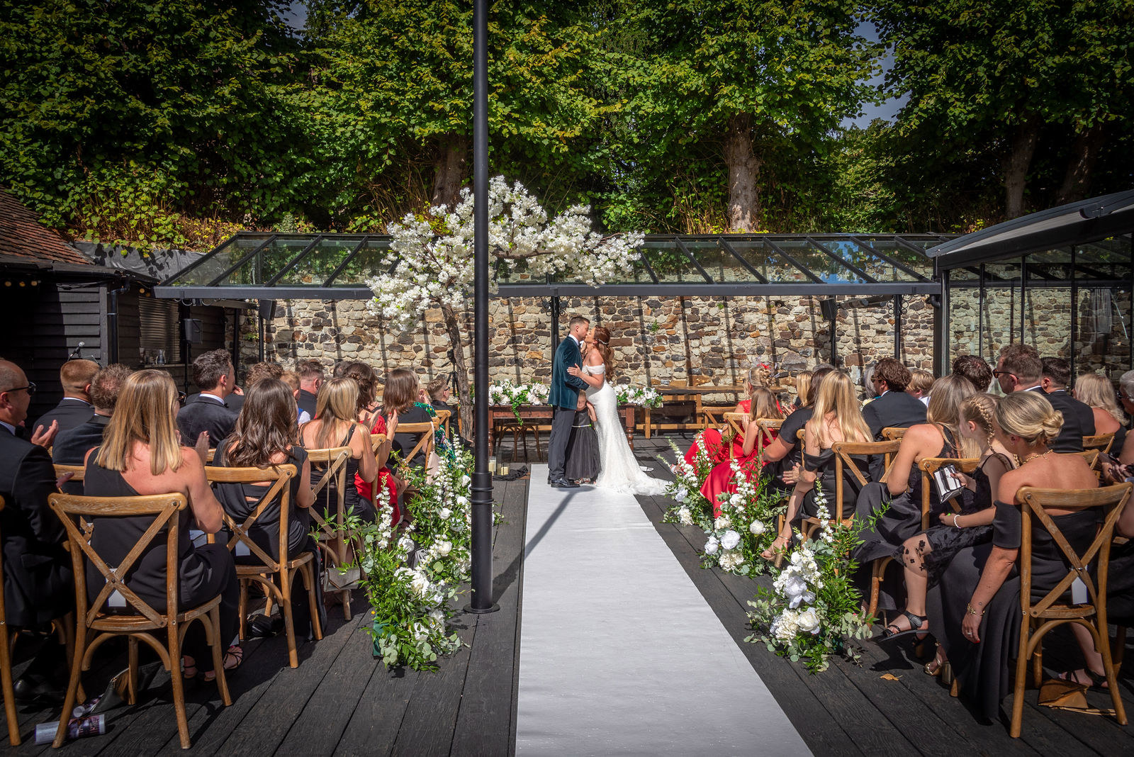 The bride and groom kiss during their ceremony at the Buttery and Glasshouse wedding venue in Kent