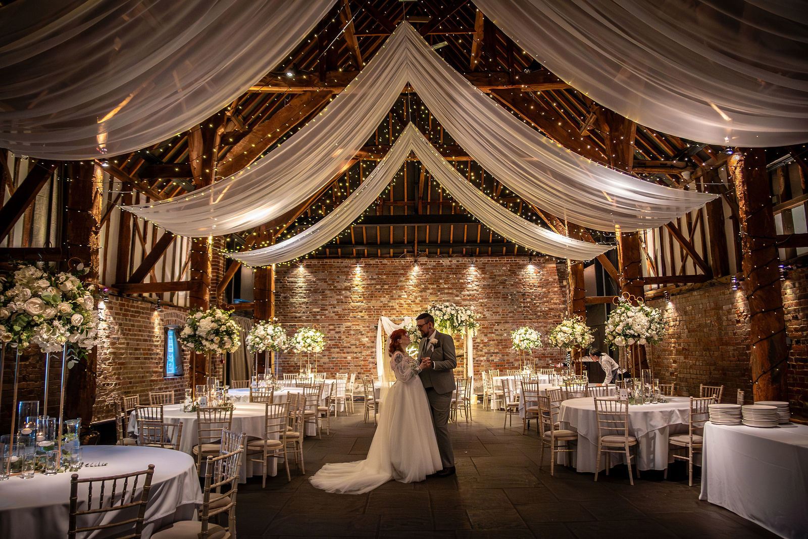 The bride and groom preparing for their wedding reception at Cooling Castle Barn wedding venue